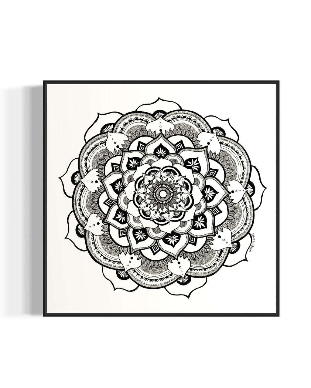 Black and white mandala art print in a black frame on a white background