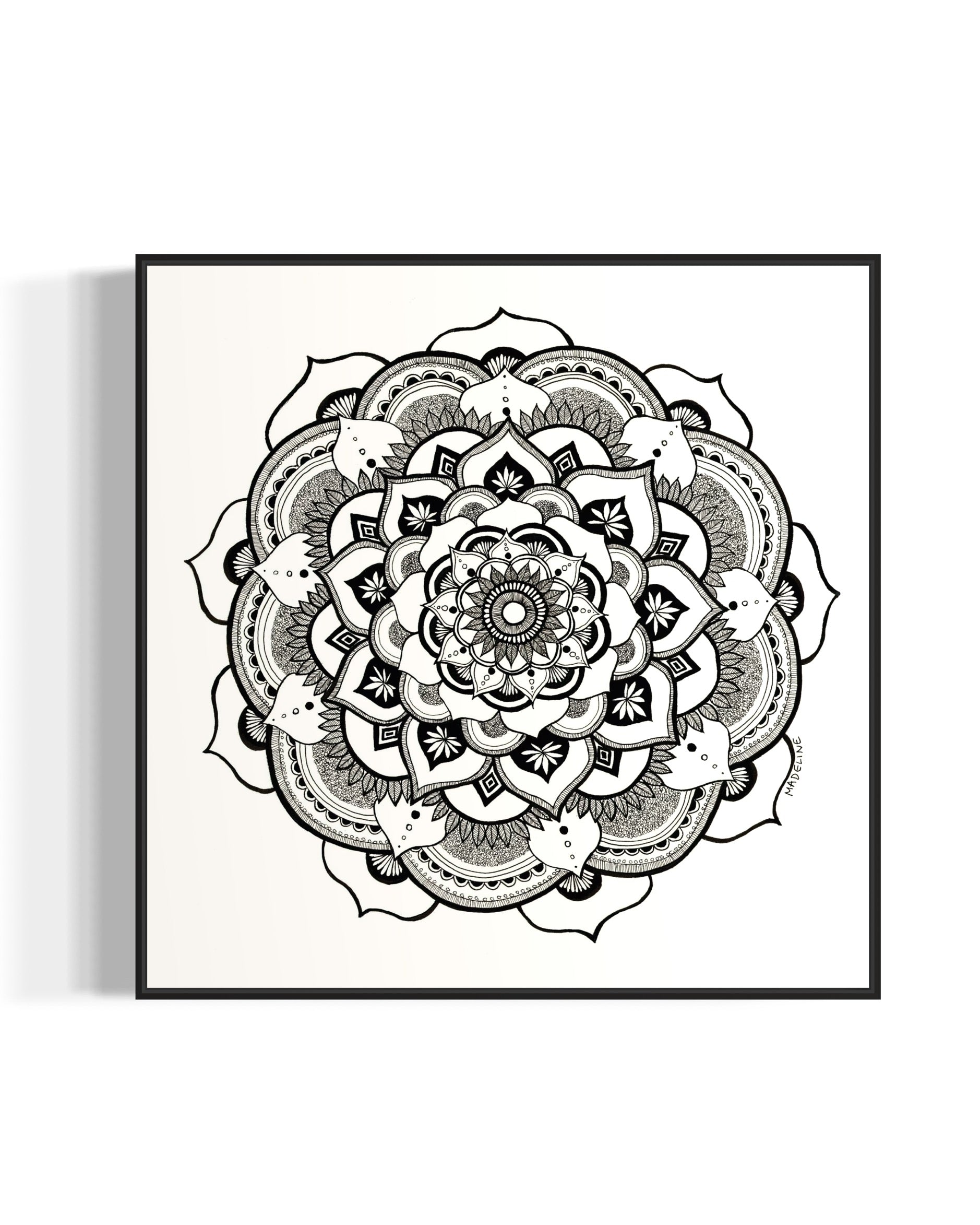 Black and white mandala art print in a black frame on a white background