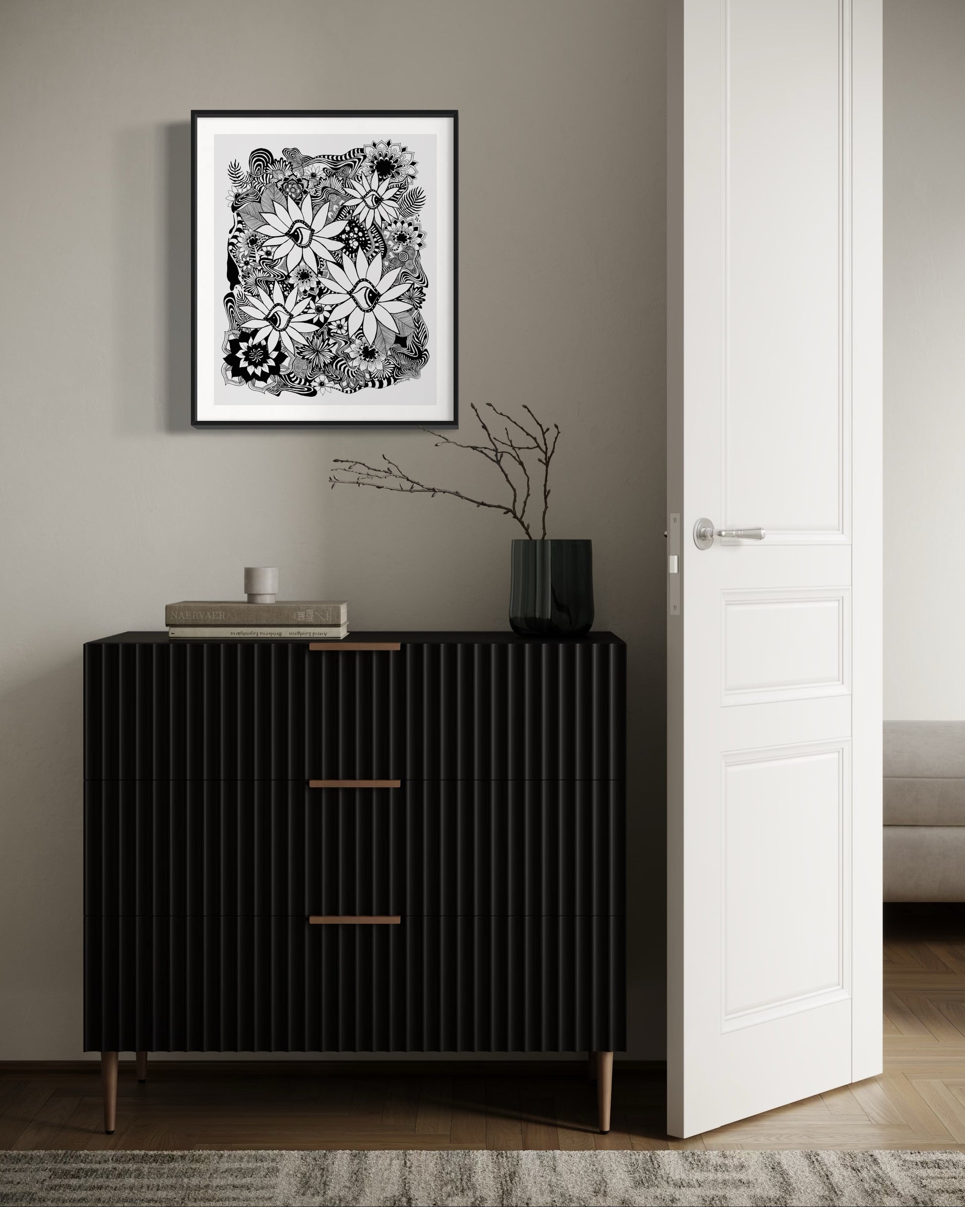 Black and white floral art print on a wall above a black cabinet.