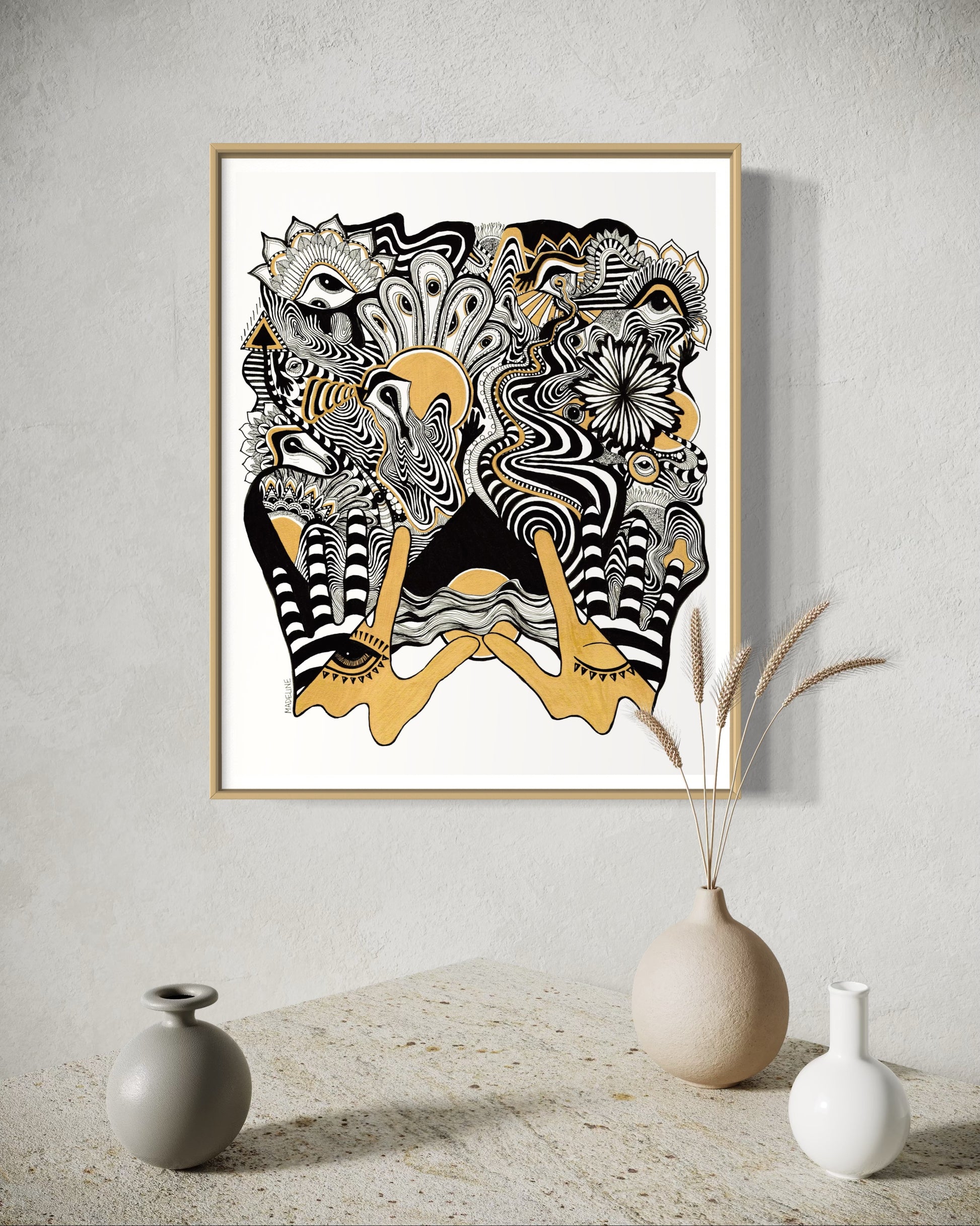 Framed abstract artwork with black, white, and gold designs coming out of two gold hands and fine linework on a white background