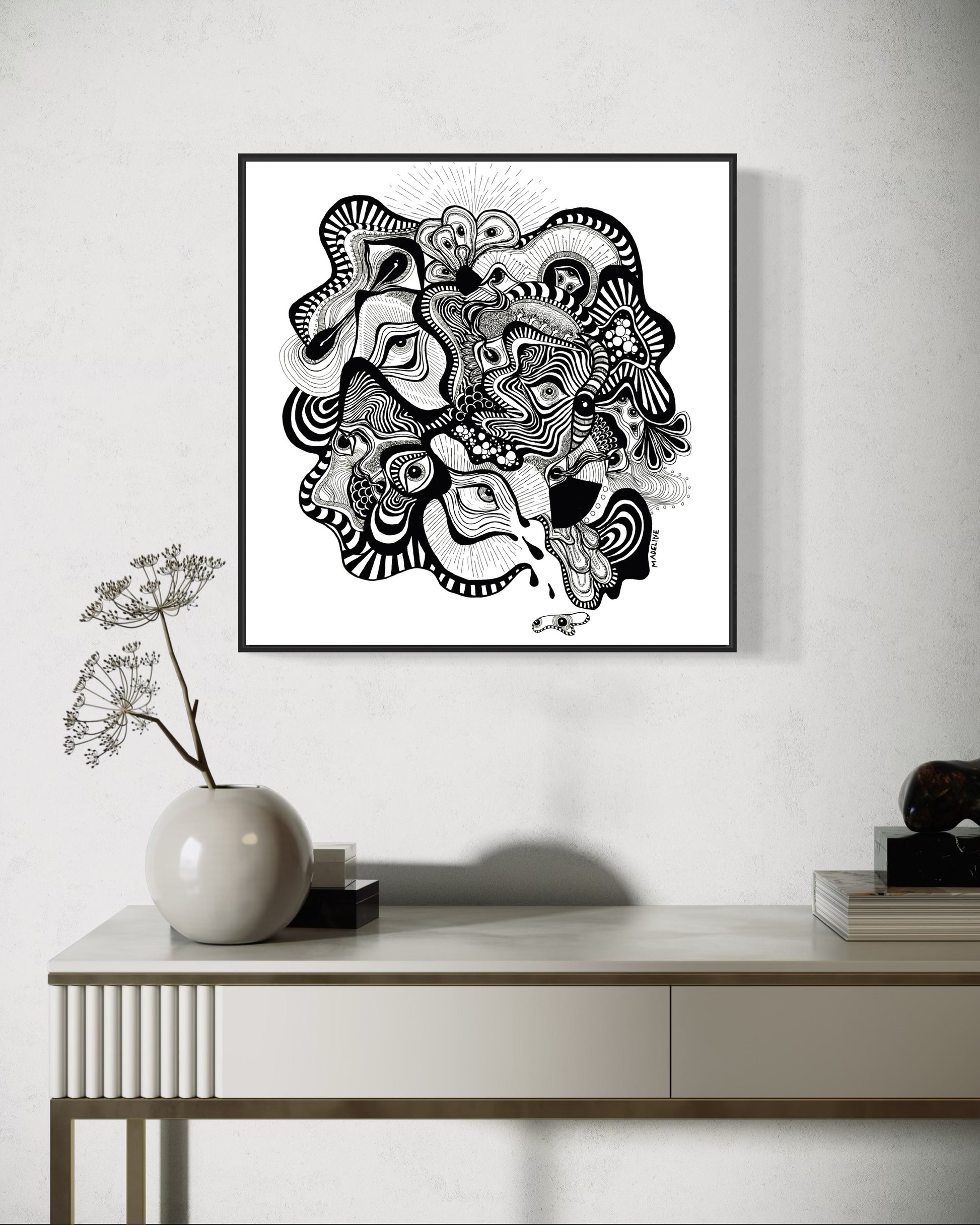 Framed black and white abstract artwork filled with eyes and whimsical linework patterns on a white background
