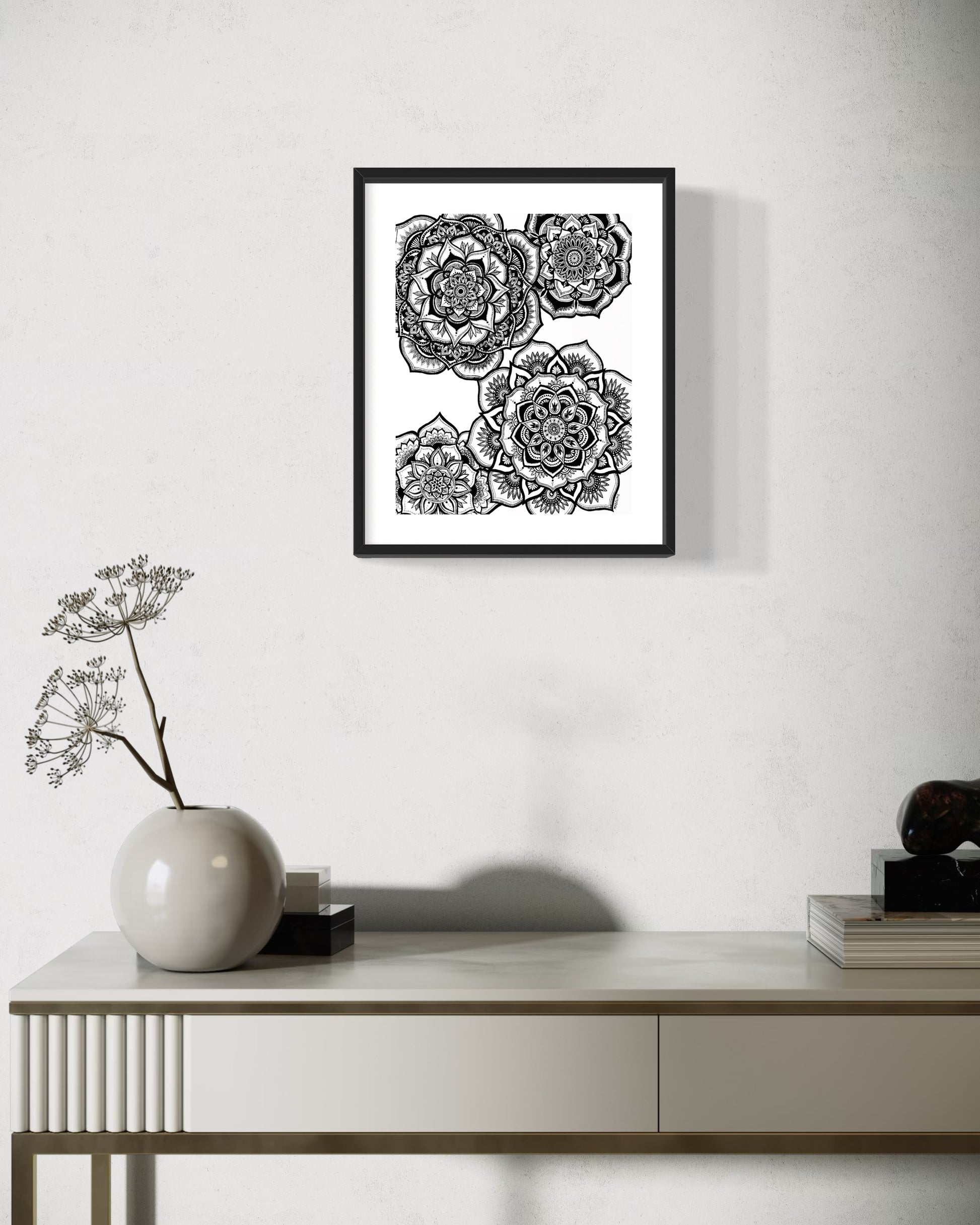 Framed black and white floral artwork on a wall above a console table.
