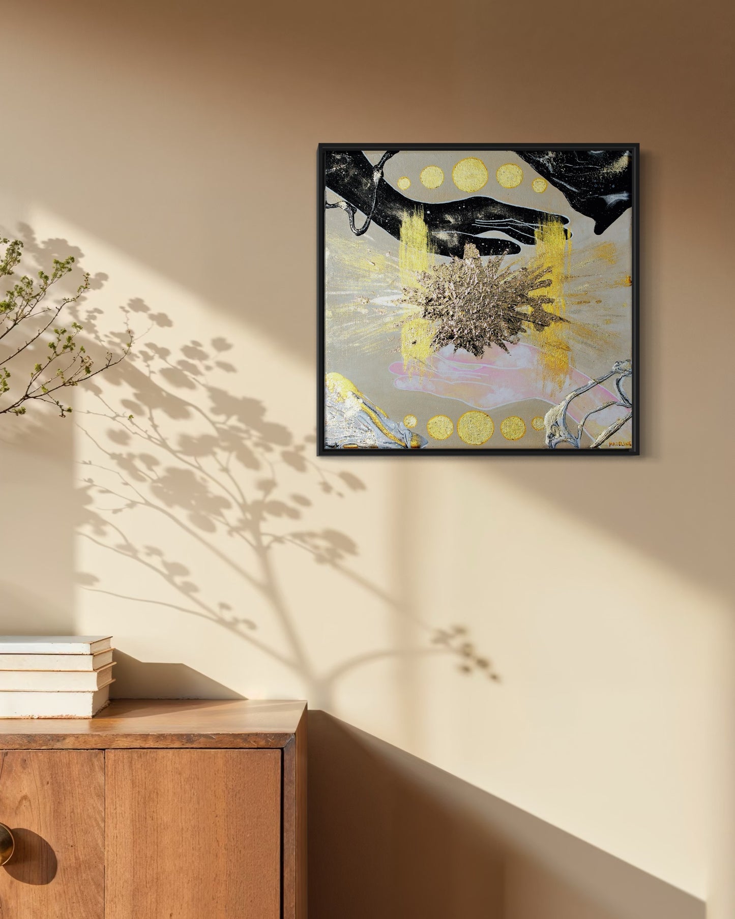 Framed abstract artwork of hands filled with the sky, an exploding gold star and geometric shapes on a tan background.
