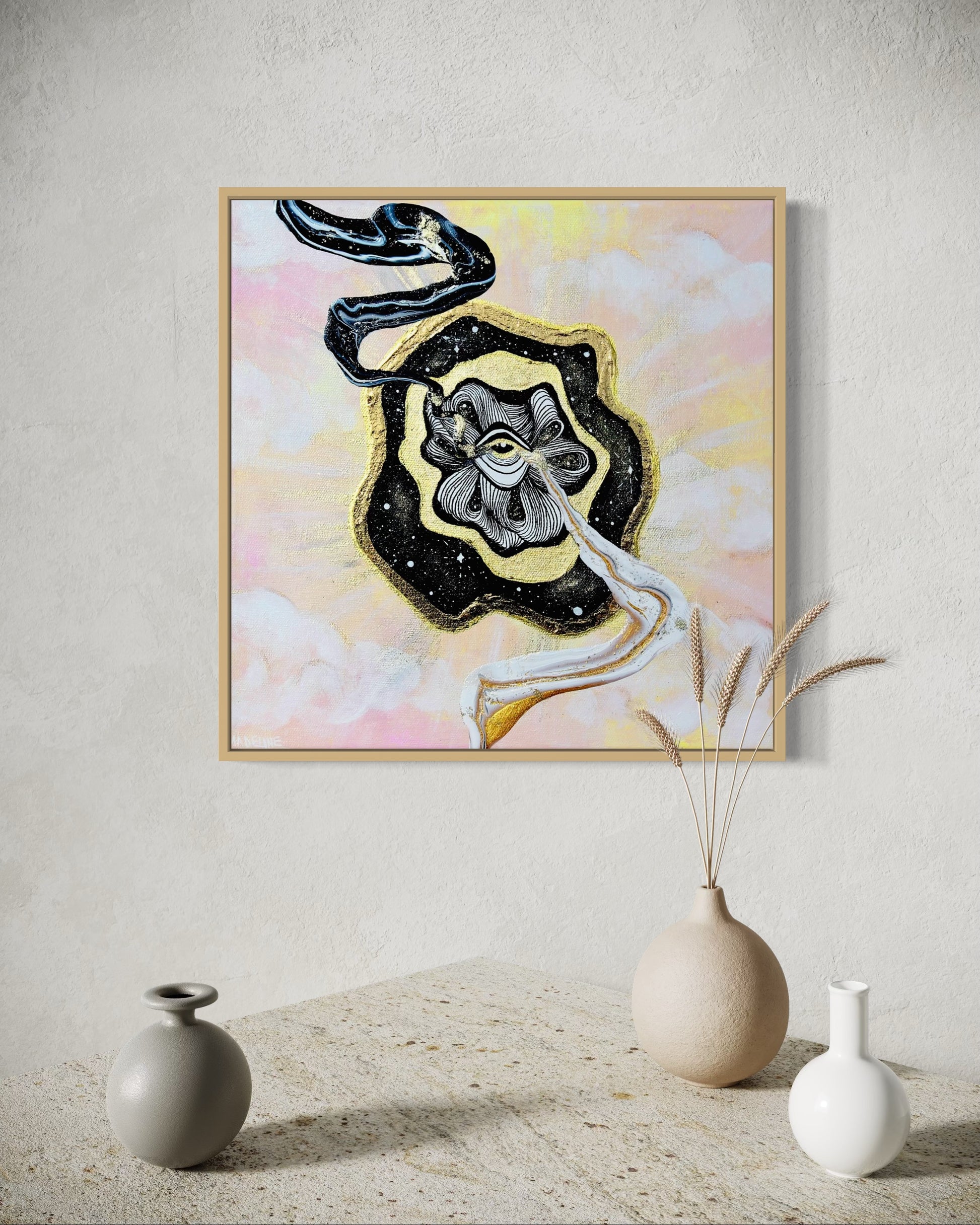 Framed artwork with a black and gold abstract swirls coming out of golden eye on a night sky over a pastel pink and yellow sky background