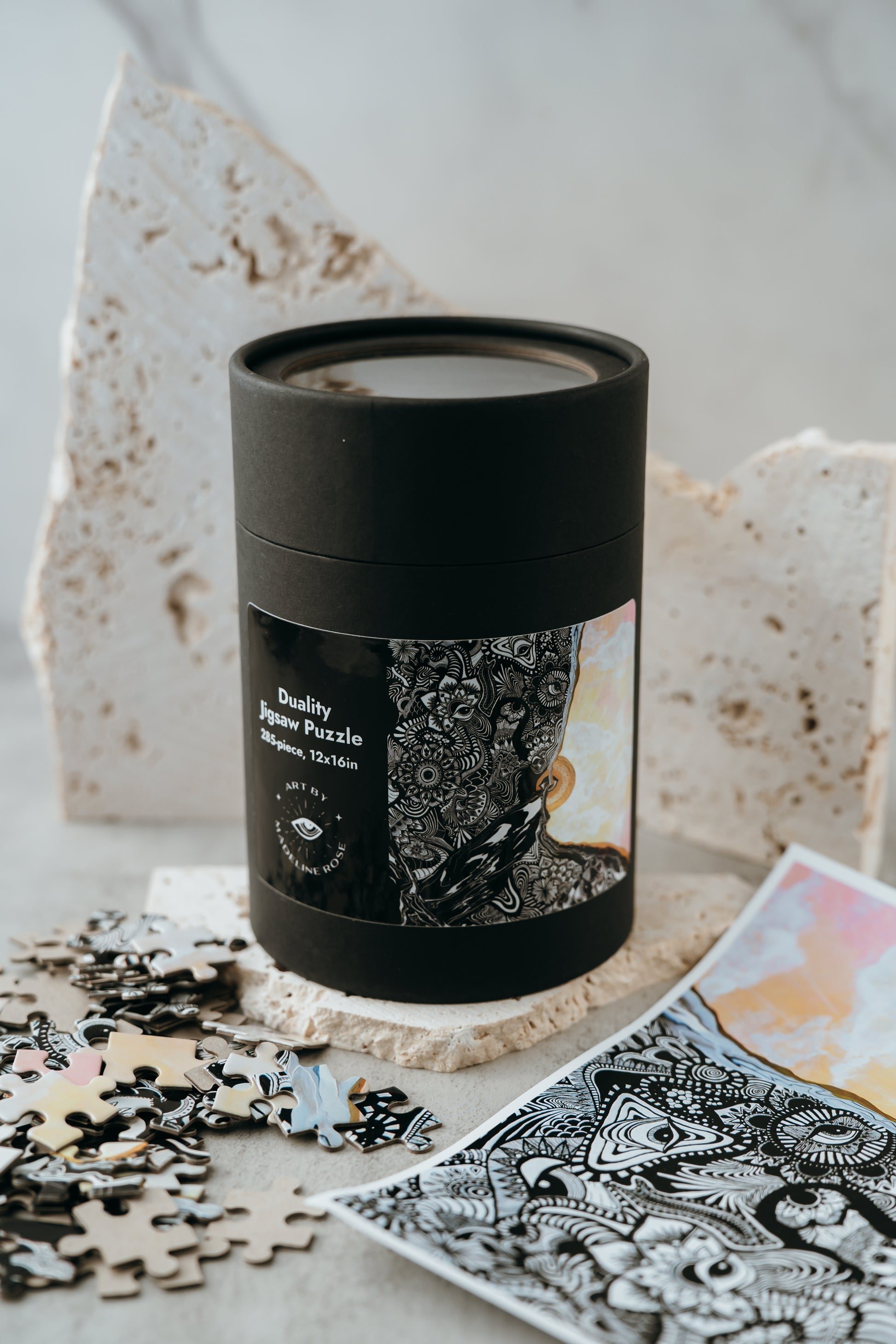 A jigsaw puzzle with pieces scattered around, partially assembled, in front of a black cylindrical container with a window displaying the finished image of the puzzle.