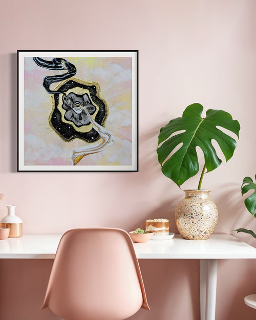 Framed abstract art on a wall with a table and chair below.