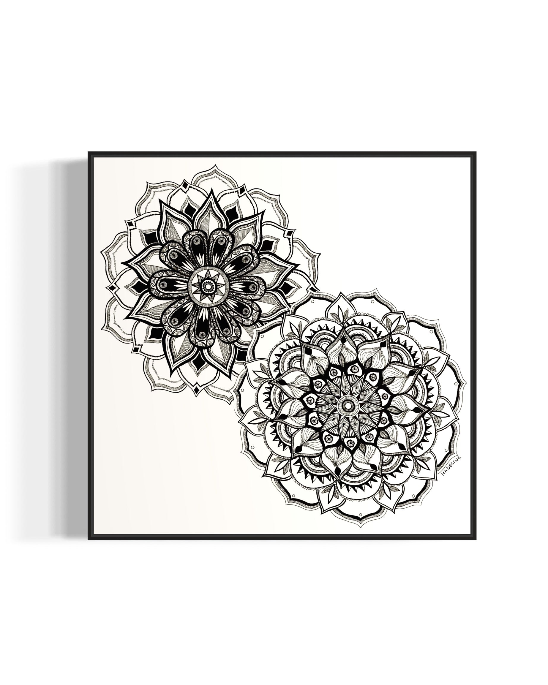 Framed artwork of two black and white mandala flower designs on a white background