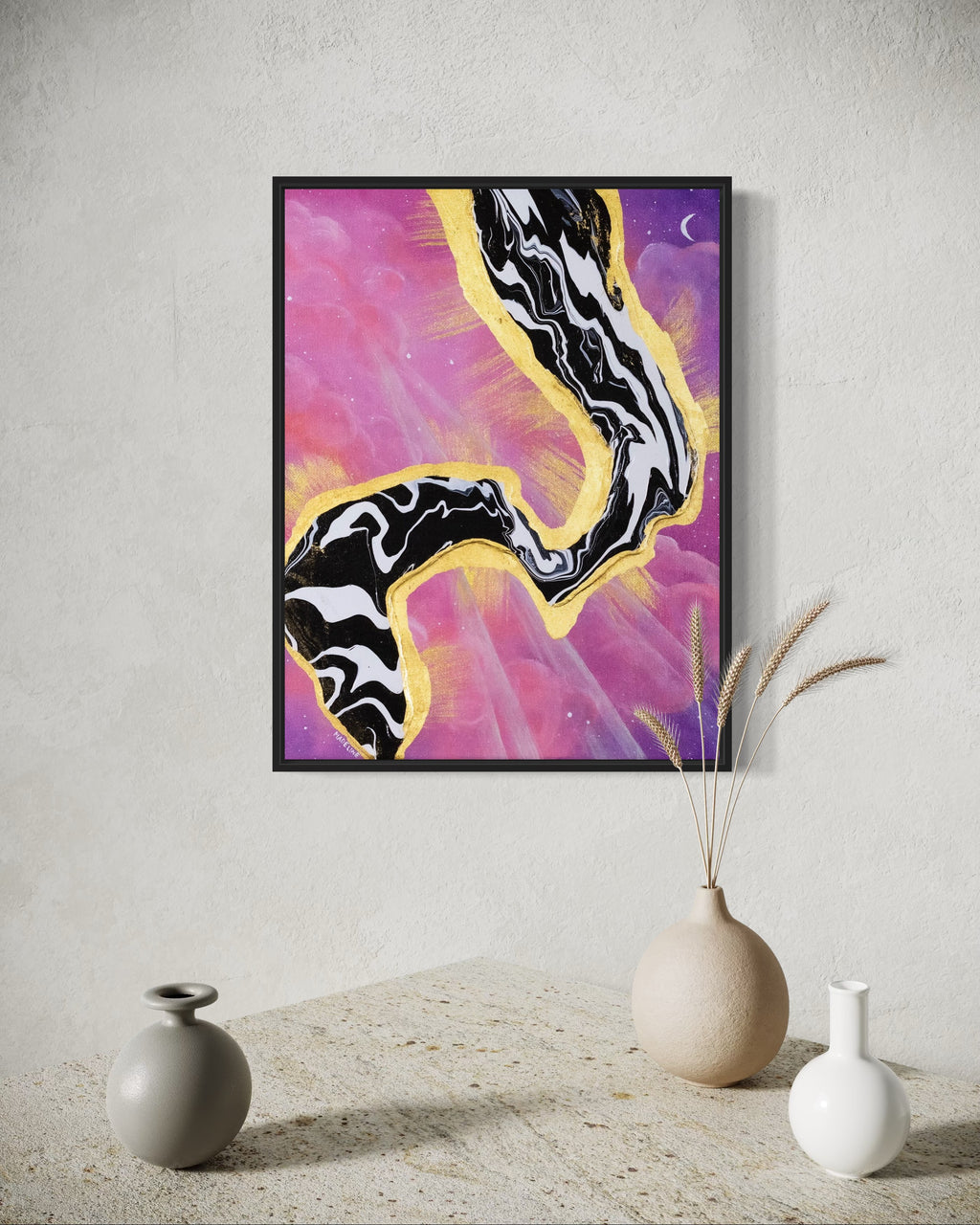 Framed artwork with abstract black and white fluid design on a pink and purple sky background with a moon and gold leaf rays