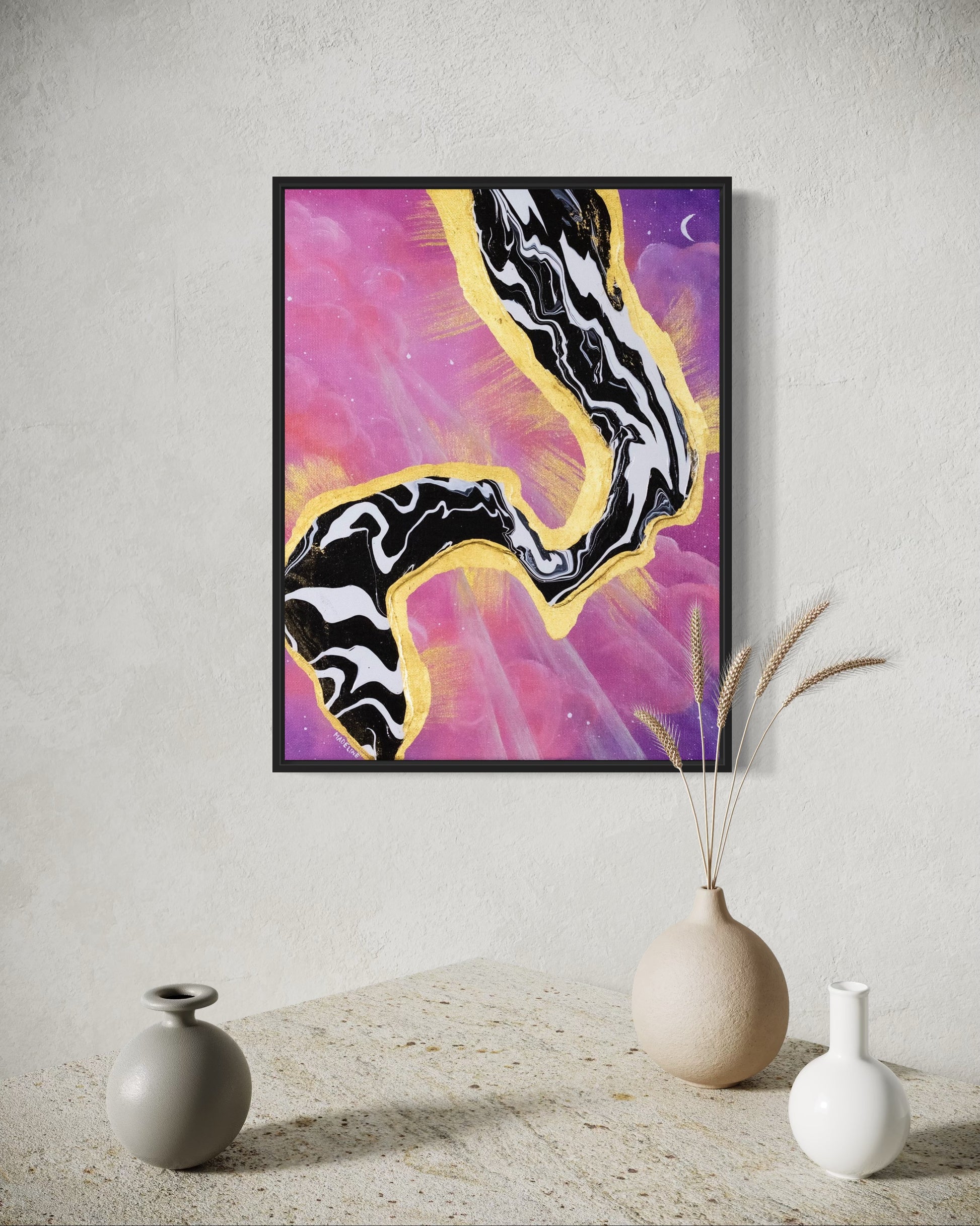 Framed artwork with abstract black and white fluid design on a pink and purple sky background with a moon and gold leaf rays